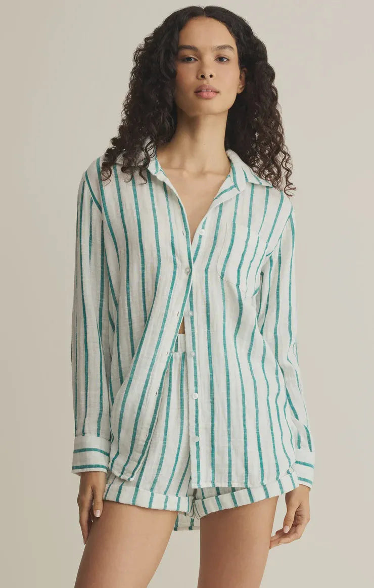 A woman wears a white and teal vertically striped long sleeve saturdays stripe button shirt