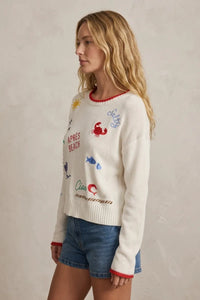 White knit day sienna sweater with colorful embroidered beach designs and red trim on neckline and cuffs