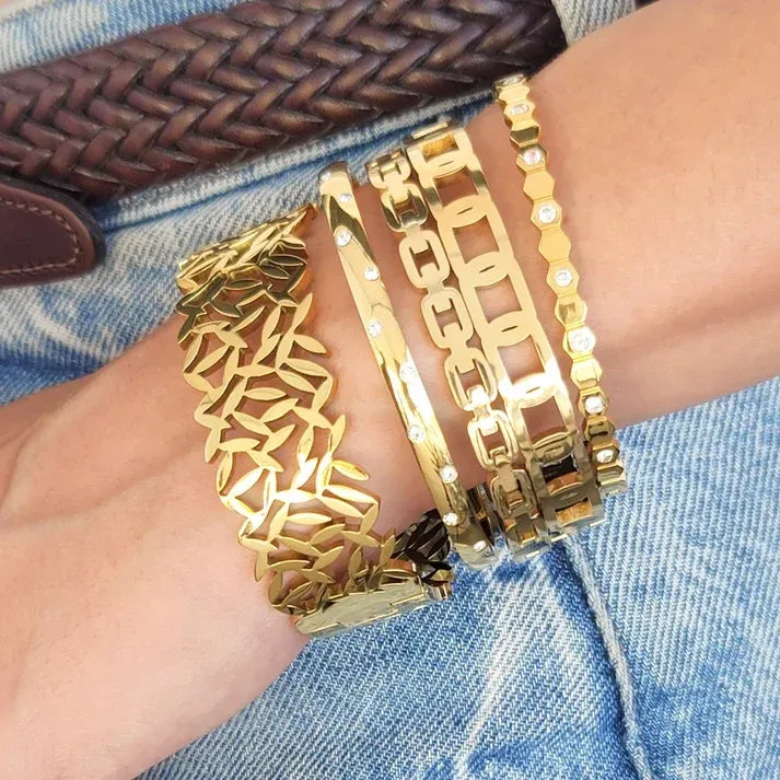 A set of four gold-toned water resistant bangles featuring intricate leaf, chain-link, and stone-embellished designs