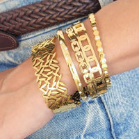 A set of four gold-toned water resistant bangles featuring intricate leaf, chain-link, and stone-embellished designs