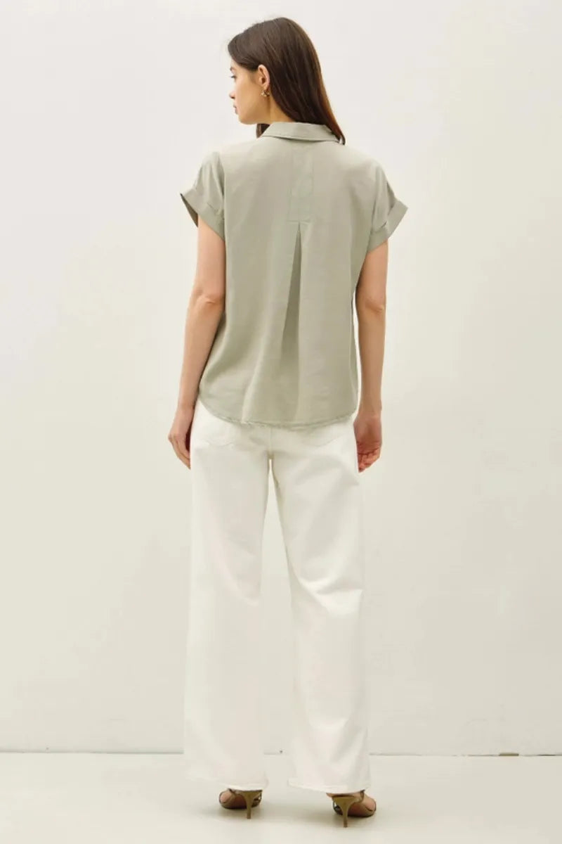 A light gray short dolman sleeve button down shirt with a subtle pleated back and crisp collar shown from the back
