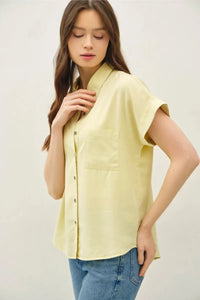 A pale yellow short dolman sleeve button shirt with collar and chest pocket for casual wear
