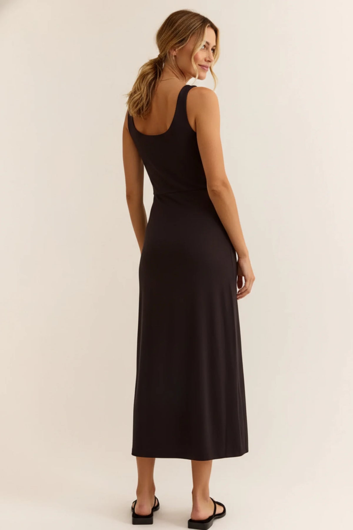 Sleek black night fitted midi dress with back cutout and flowing fabric
