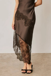 A sleek dark brown satin slip dress with asymmetrical lace trim and intricate black lace detailing on side and hem