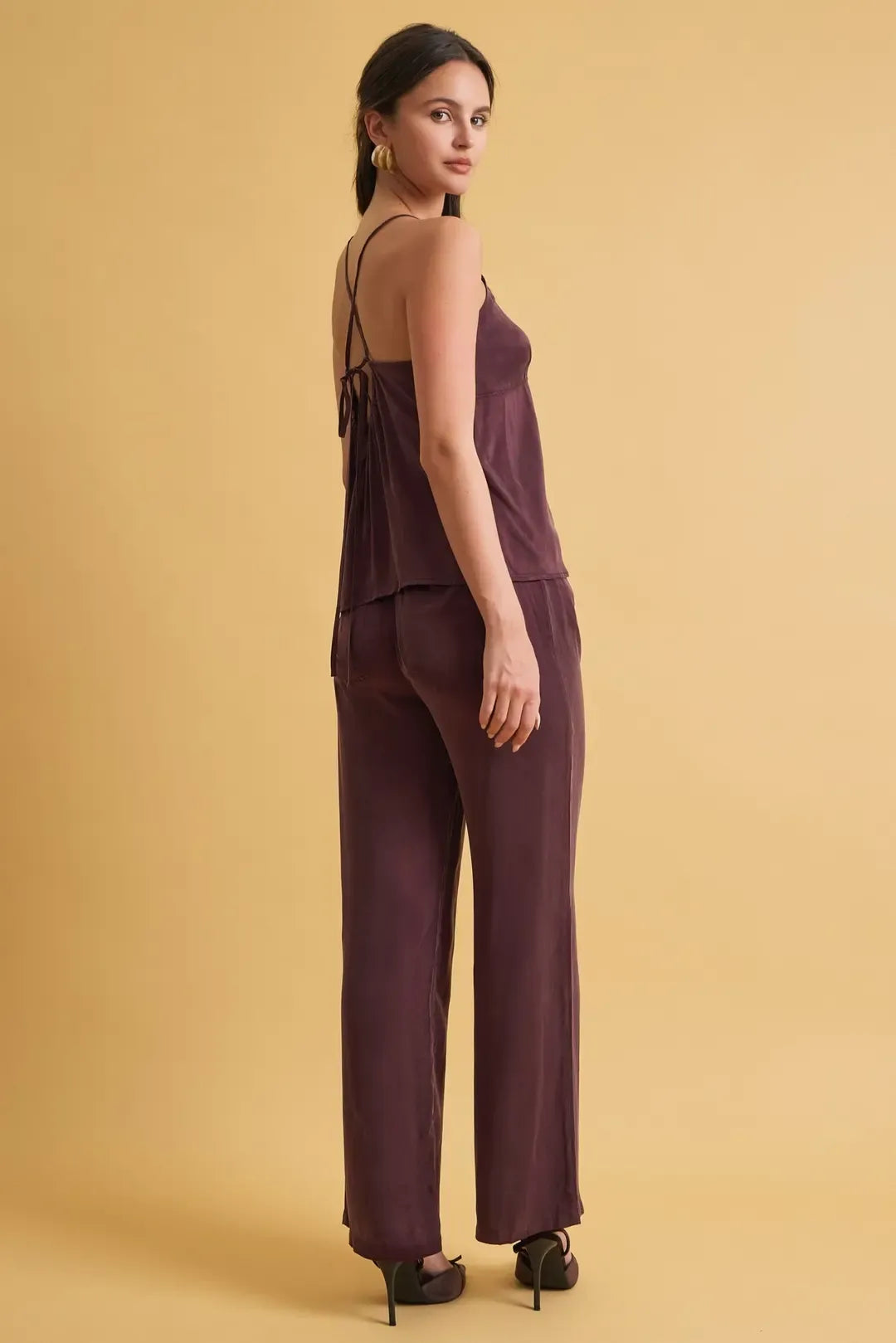 A sleek deep purple satin jumpsuit featuring a loose fit wide leg pants design with back tie detail