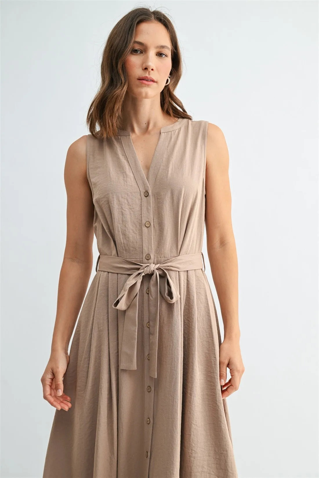 A sleeveless beige tie midi dress with v neck button front design and matching self-tie belt in lightweight fabric