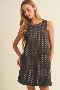 A sleeveless black polka dot mini dress with white dots and two front pockets perfect for casual wear