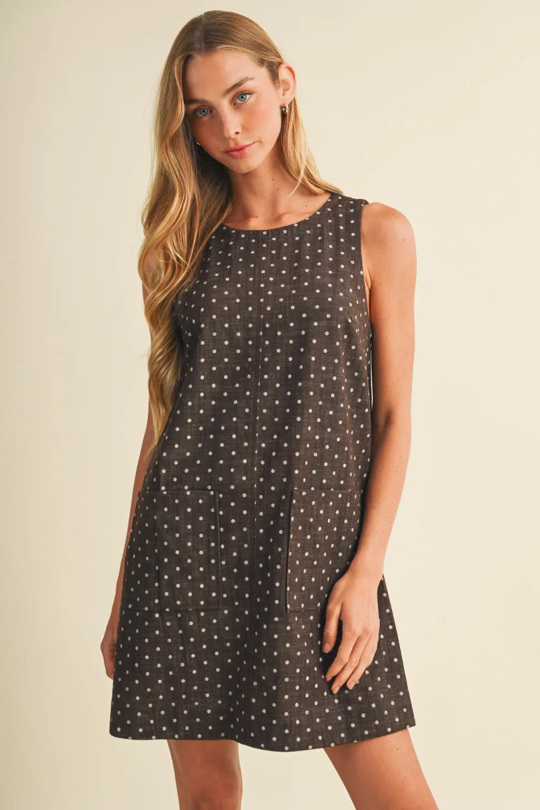 Polka dot sleeveless mini dress in dark gray with subtle white dots and two front pockets for casual wear