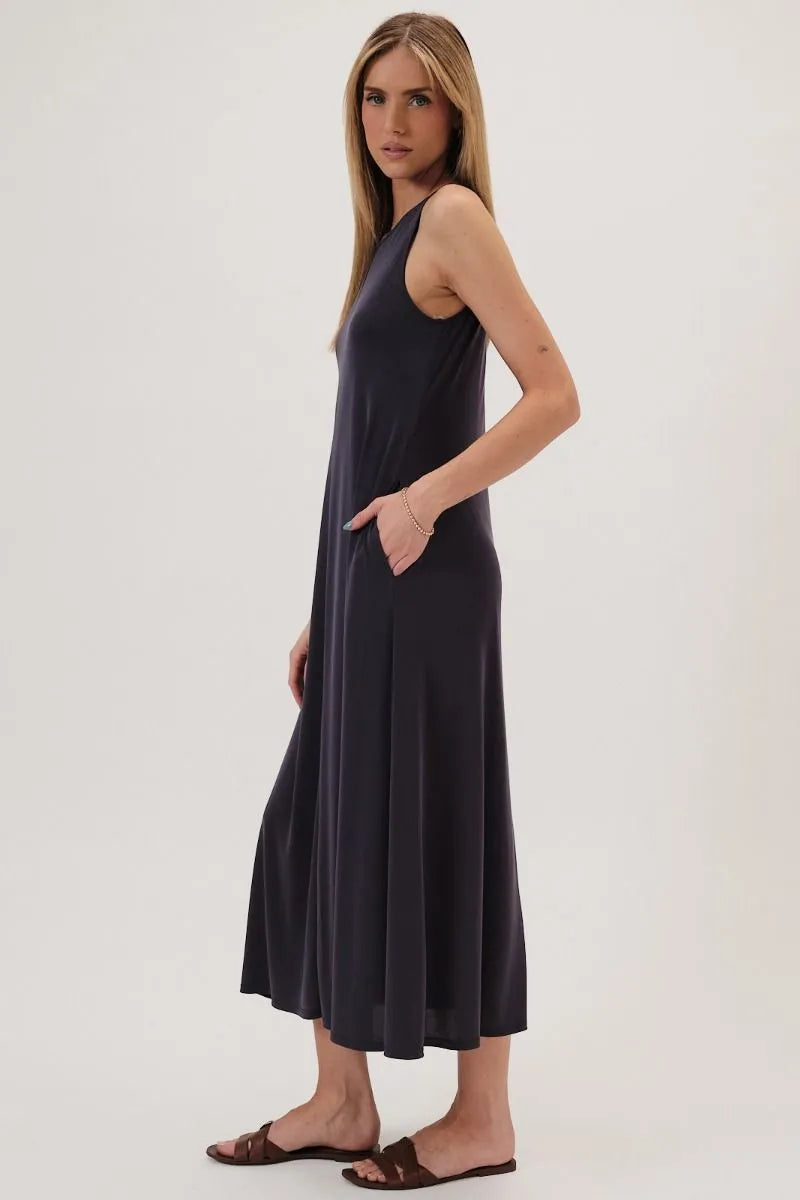 A flowing sleeveless dark gray maxi dress with round neck narrow shoulder and subtle pleats along the skirt
