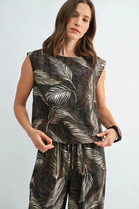 A sleeveless dark-toned leaf print wide shoulder top with bold white and beige tropical leaf designs