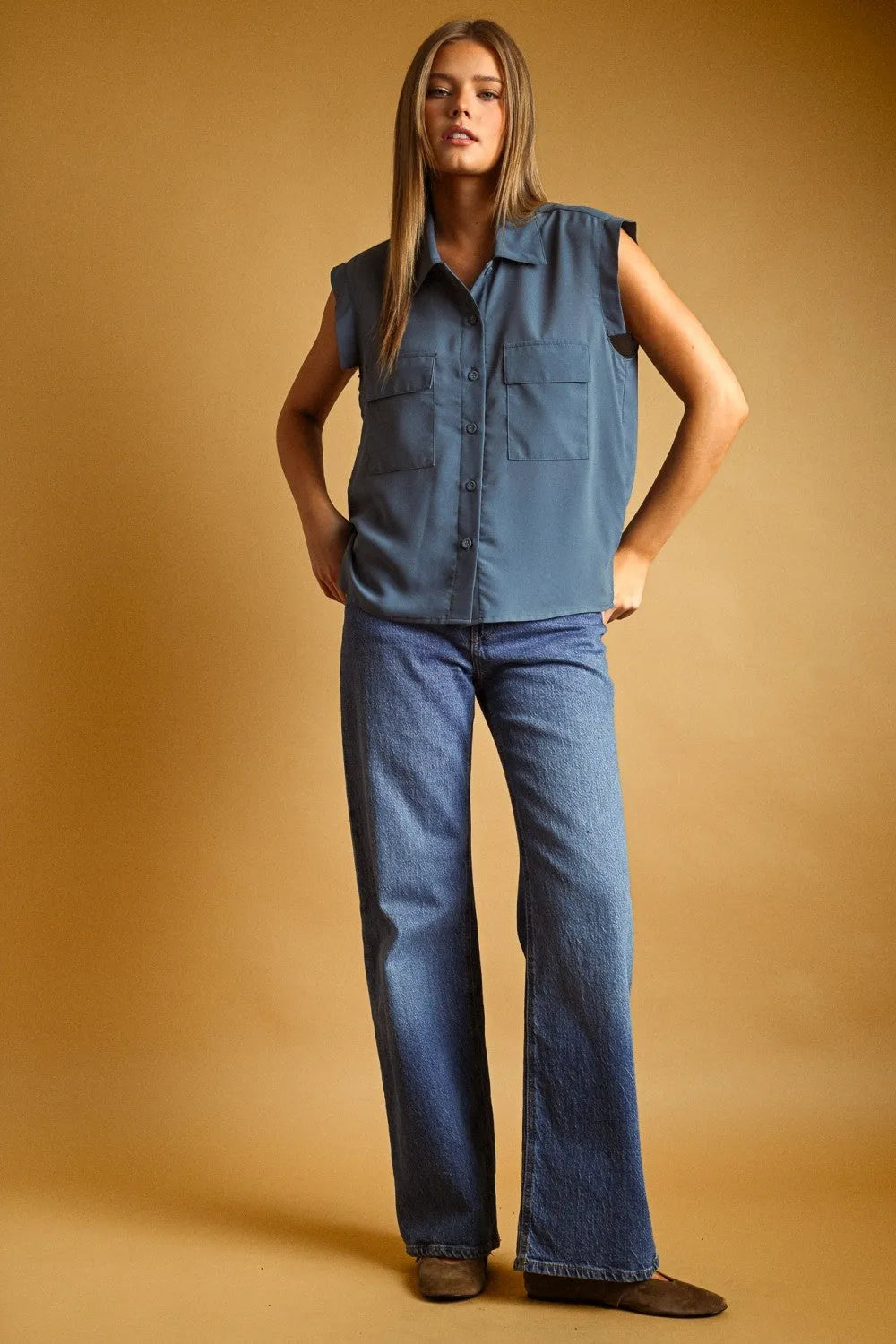 A soft blue sleeveless chiffon blouse with front pocket button detail and a button-down collar