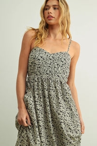 A flowing sleeveless floral print maxi summer dress with delicate straps and a fitted bodice in black on off-white fabric