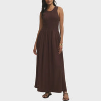 A sleeveless brown juniper smocked maxi dress featuring a ribbed bodice and flowing floor-length skirt