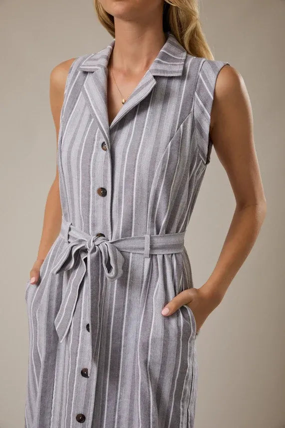 A sleeveless gray and white striped button-down midi dress with a matching waist tie belt at the waist