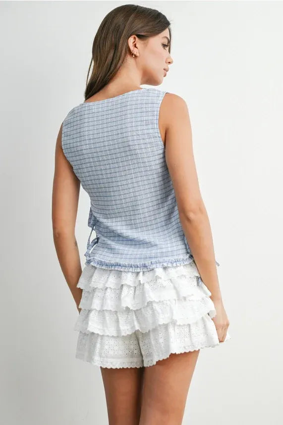 Back view of a sleeveless light blue and white checkered ladder lace blouse with ruched ties and ladder lace detail
