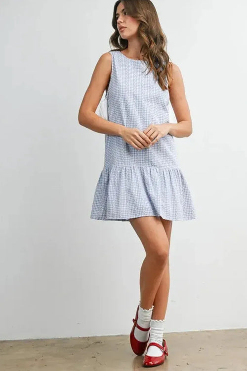 A sleeveless light blue and white gingham flounce mini dress with a tiered hem and side tie detail