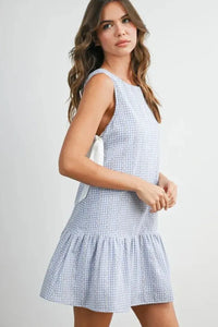 Sleeveless light blue and white gingham flounce mini dress with ruffled hem and back tie detail showing the back side