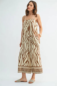 A flowing sleeveless border print jumpsuit in cream and brown zebra print with geometric trim at the hem