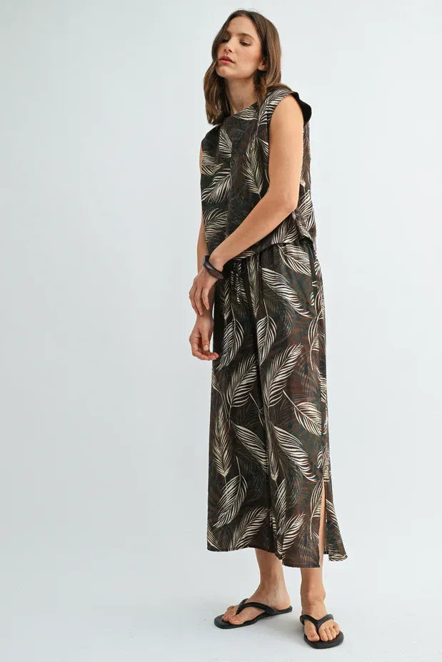 A flowing sleeveless maxi dress in dark olive with an elegant white leaf print elastic waist pattern