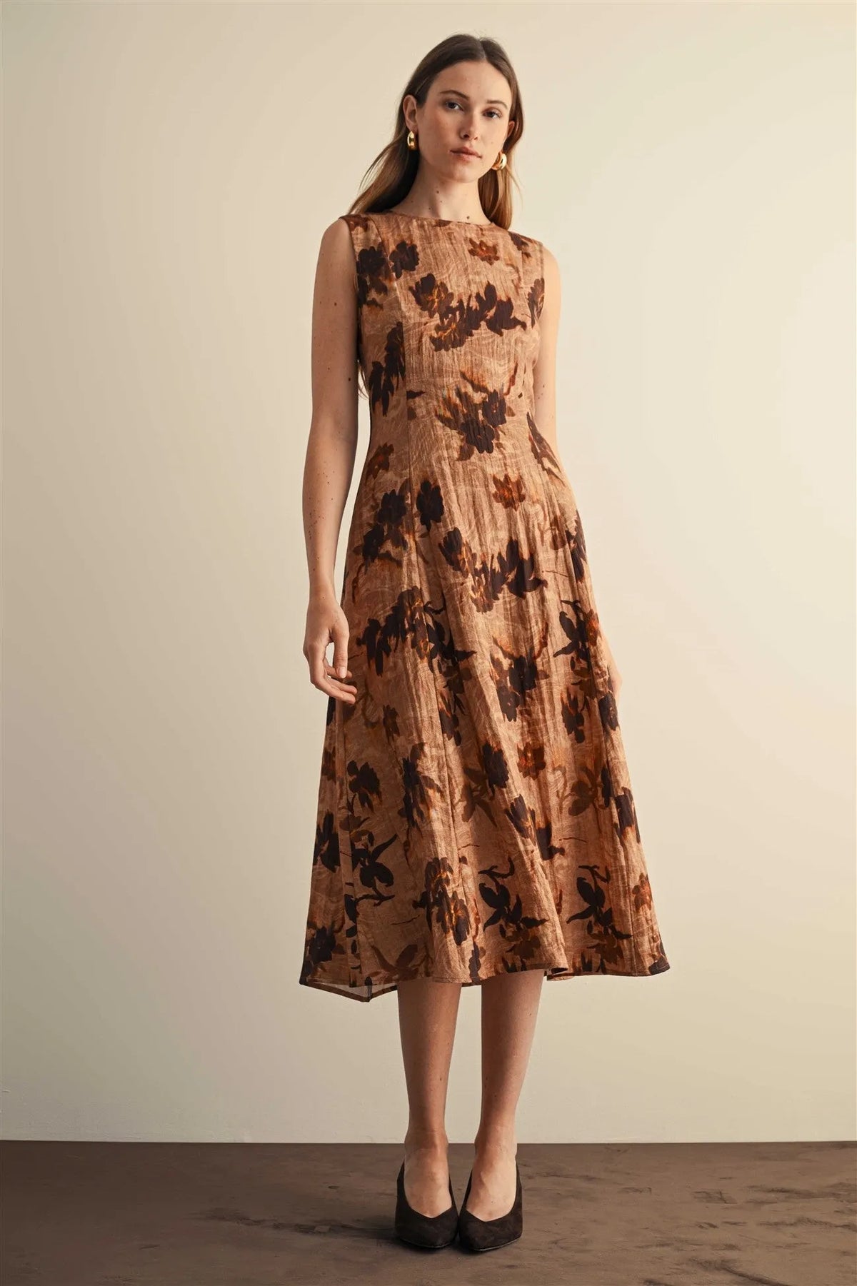 Flower print sleeveless midi dress in warm beige fabric with dark brown floral pattern and subtle vertical pleats