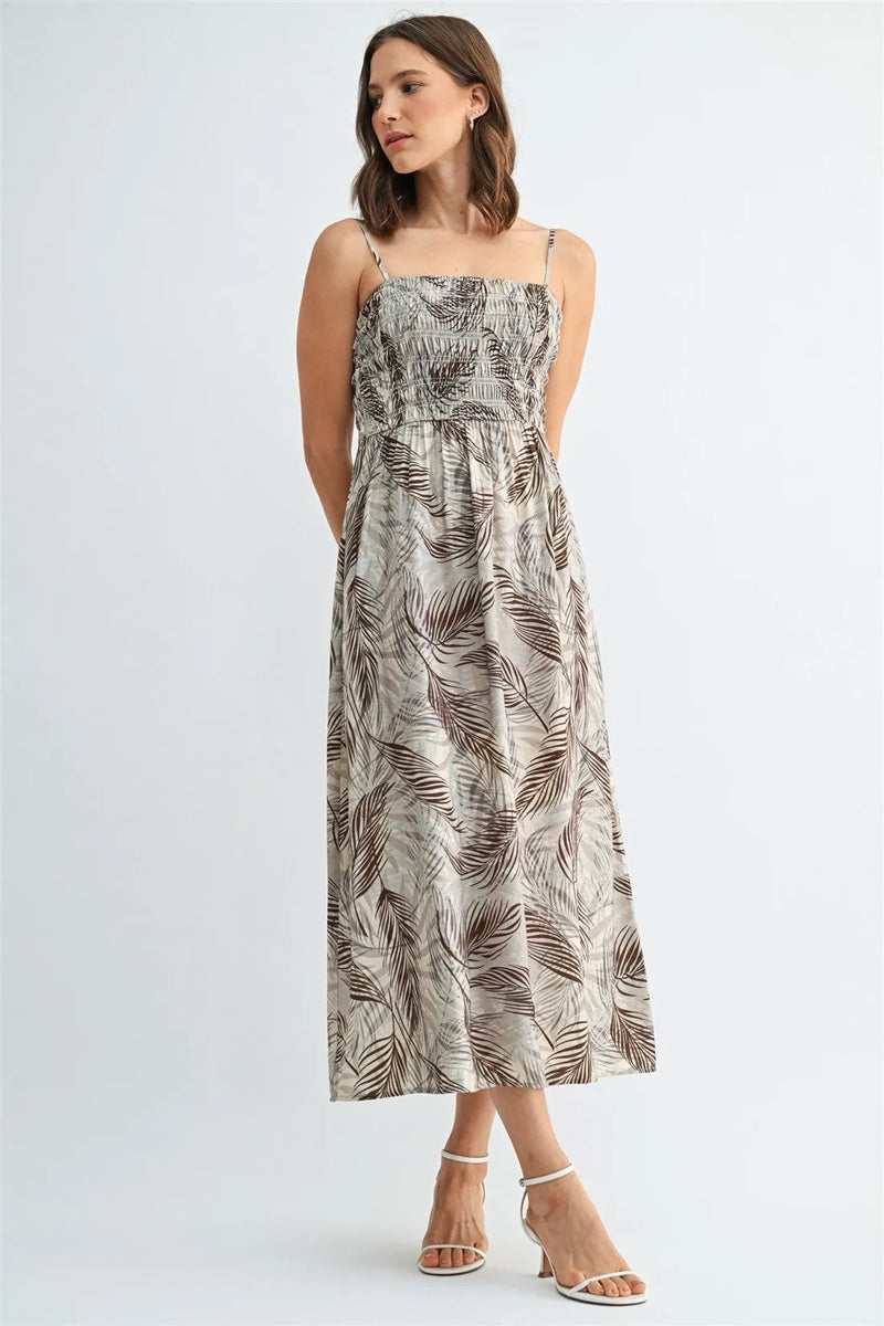 A flowing beige midi dress with elegant brown leaf print smocking and delicate spaghetti straps