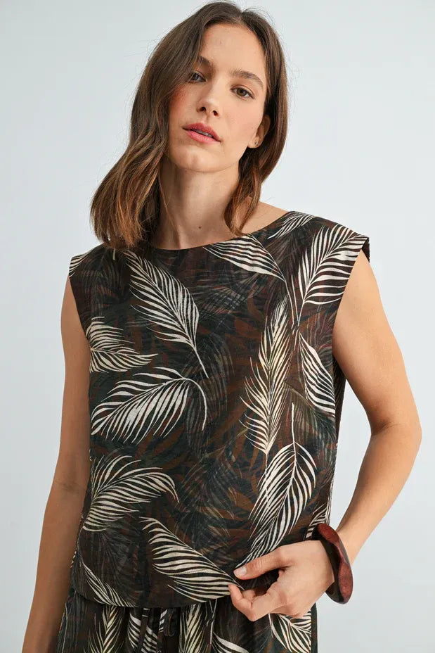 A sleeveless wide shoulder top in sheer dark brown fabric with an intricate white and black leaf print wide design
