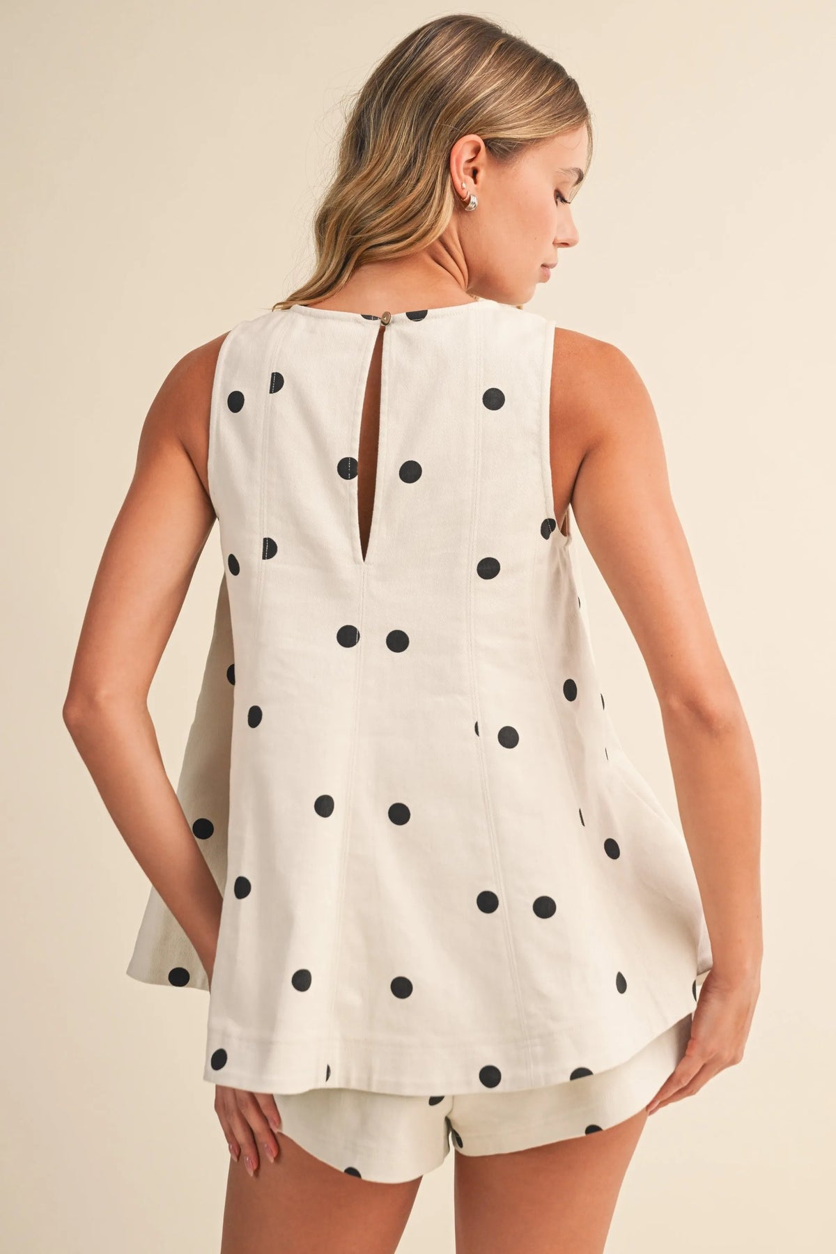 Back view of a sleeveless white top with black polka dots and keyhole detail paired with polka dot denim elastic short