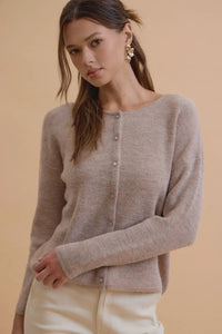 A soft beige wool ribbed cardigan with round neck and button closure perfect for layering in cool weather