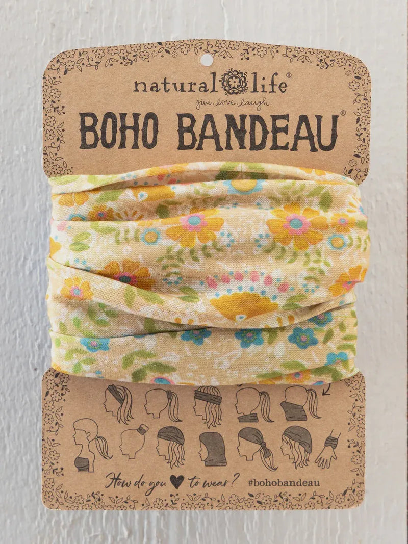 A soft cream-colored boho bandeau headband with taupe mandala floral design wrapped on a cardboard display card