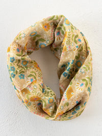 A soft cream-colored boho bandeau headband with taupe mandala floral pattern in yellow green and blue