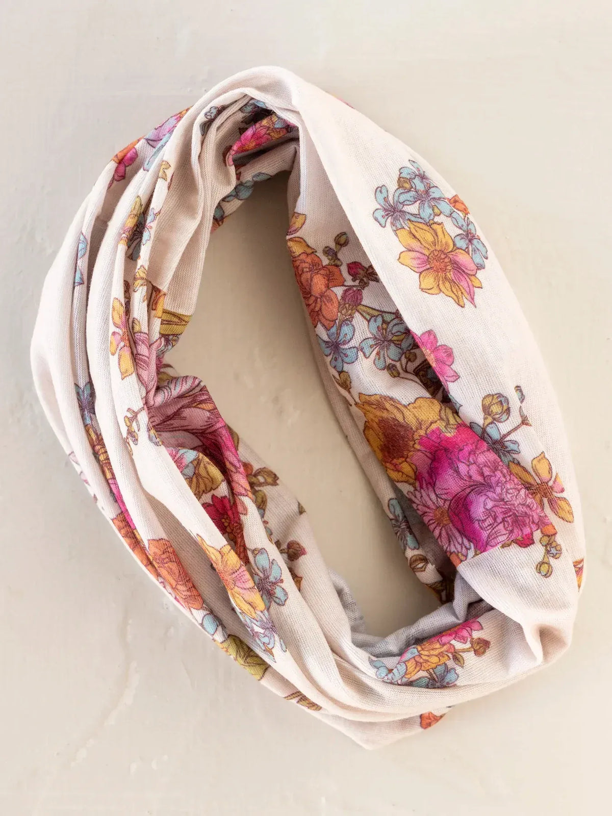 A soft cream-colored full boho bandeau headband in english garden cream with vibrant pink yellow and blue floral pattern