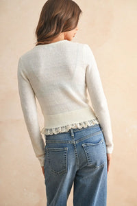 A soft cream-colored lace contrasted knitted cardigan featuring delicate lace trim along the hem