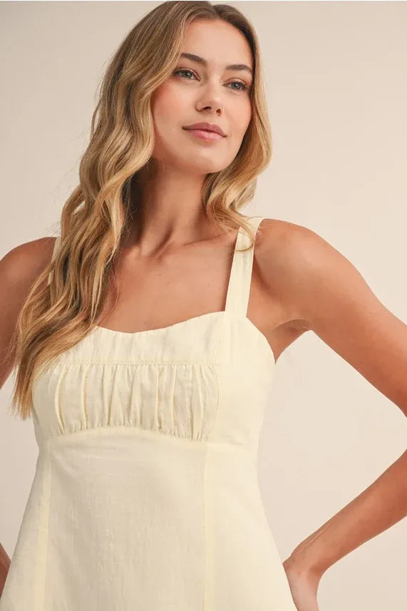 A soft cream shirring bra cotton mini dress with delicate ruched neckline and thin straps in cotton mini dress style