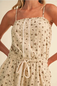 A soft cream ditsy floral sleeveless lace barrel jumpsuit with delicate brown patterns and thin spaghetti straps