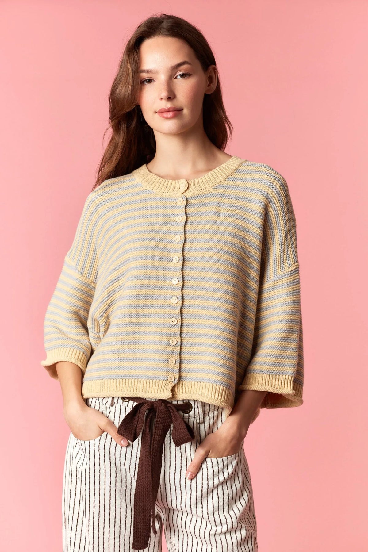 A cream and light blue striped knit cardigan with a button front featuring a curly edge oversized design