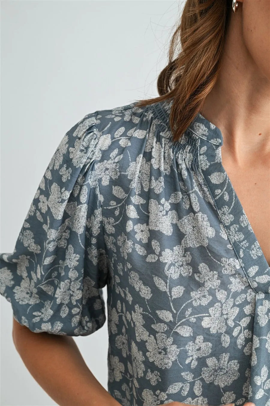 A soft gray v-neck smocking blouse with delicate white floral pattern and puffed short sleeves for women’s boho chic clothing