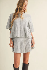 A soft gray two-piece set with a flowing cape top and pleated mini skirt in wide rib knit material