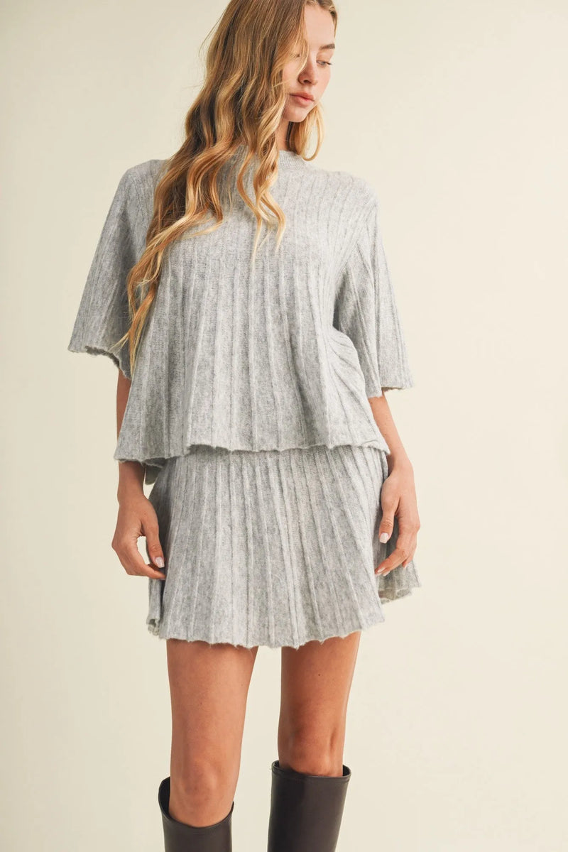 A soft gray two-piece set with a flowing cape top and pleated mini skirt in wide rib knit material