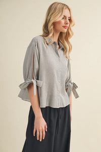 A soft gray and white striped tie cuff button up blouse with puffed sleeves tied at the cuffs
