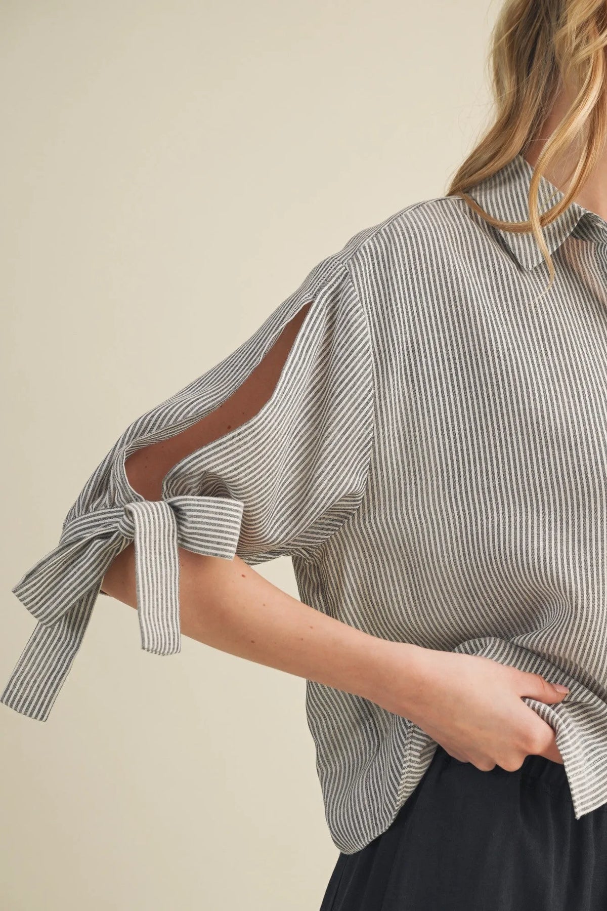 Soft gray and white striped tie cuff button front top with relaxed fit and cut-out sleeves tied into bows at cuffs