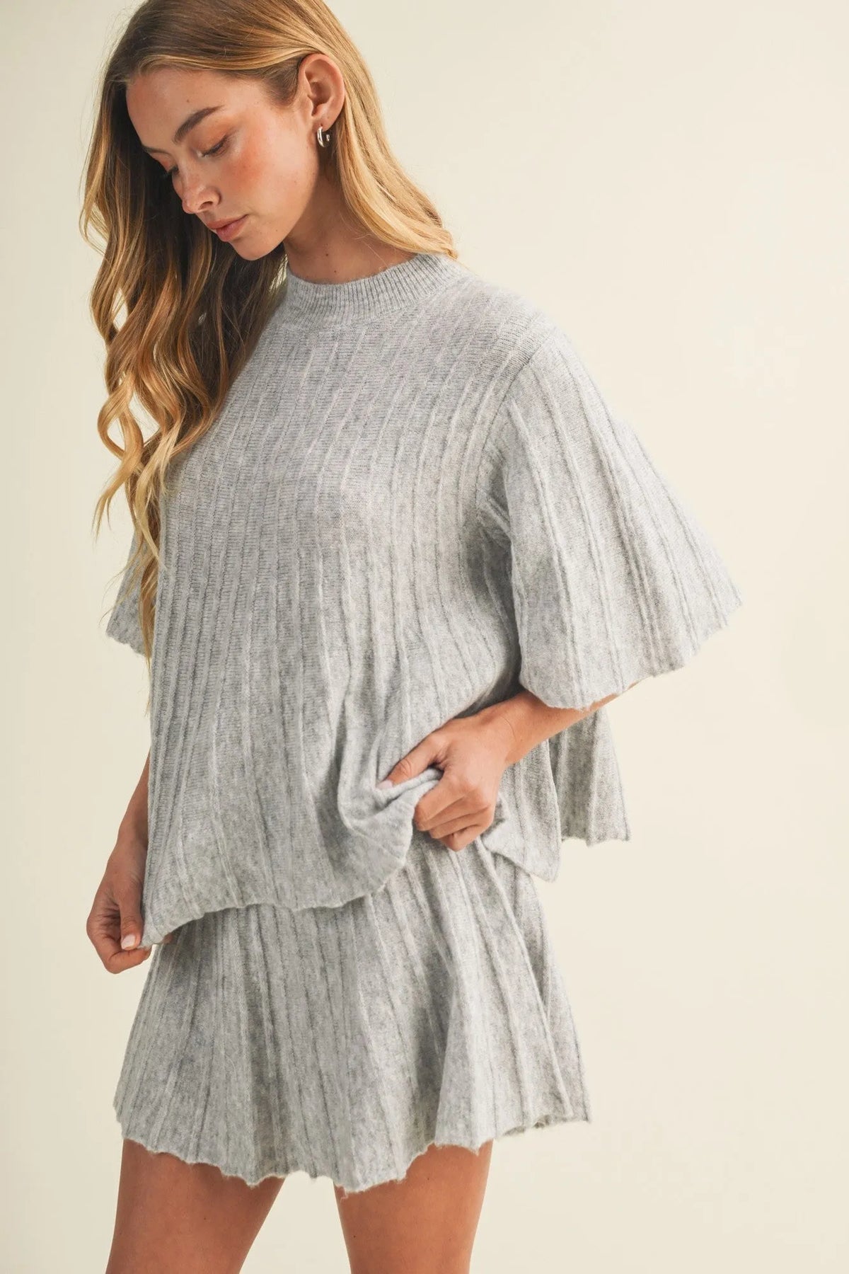 A soft heather gray rib knit two-piece set featuring a bell sleeve wide rib knit pullover sweater with cape sleeves and a flared skirt