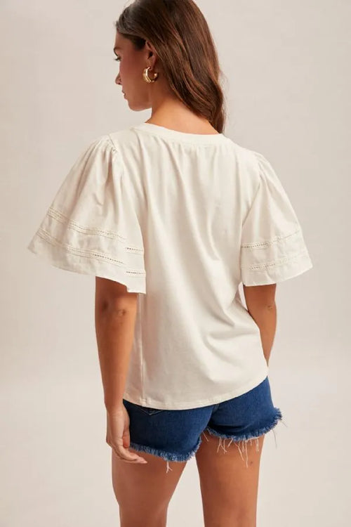 A soft ivory wing sleeve blouse featuring puffed sleeves and delicate lace trim along the cuffs
