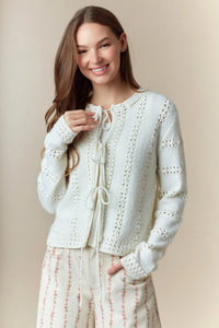 A soft ivory hole stripe bows front tie cardigan with delicate lace detailing and knit fabric