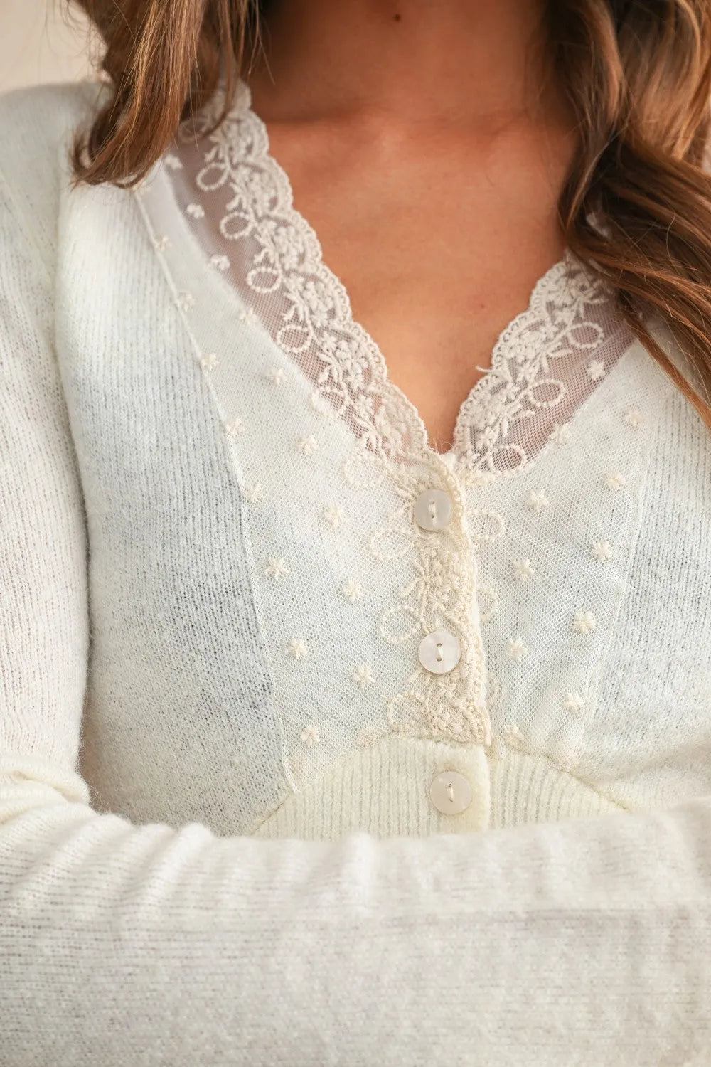 A soft ivory lace contrasted knitted cardigan with delicate lace trim and subtle embroidered floral details