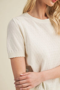 A soft ivory starburst pointelle puff sleeve knit top with short sleeves and subtle textured pattern