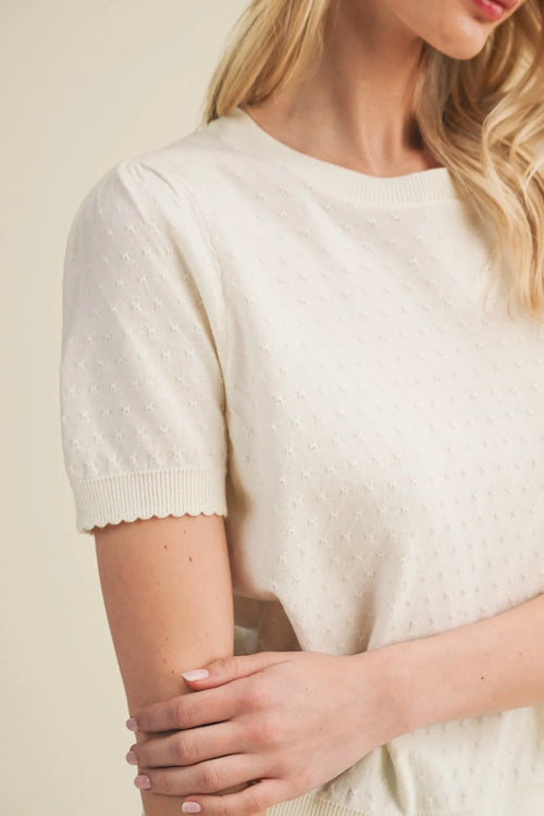 A soft ivory starburst pointelle puff sleeve knit top with short sleeves and subtle textured pattern