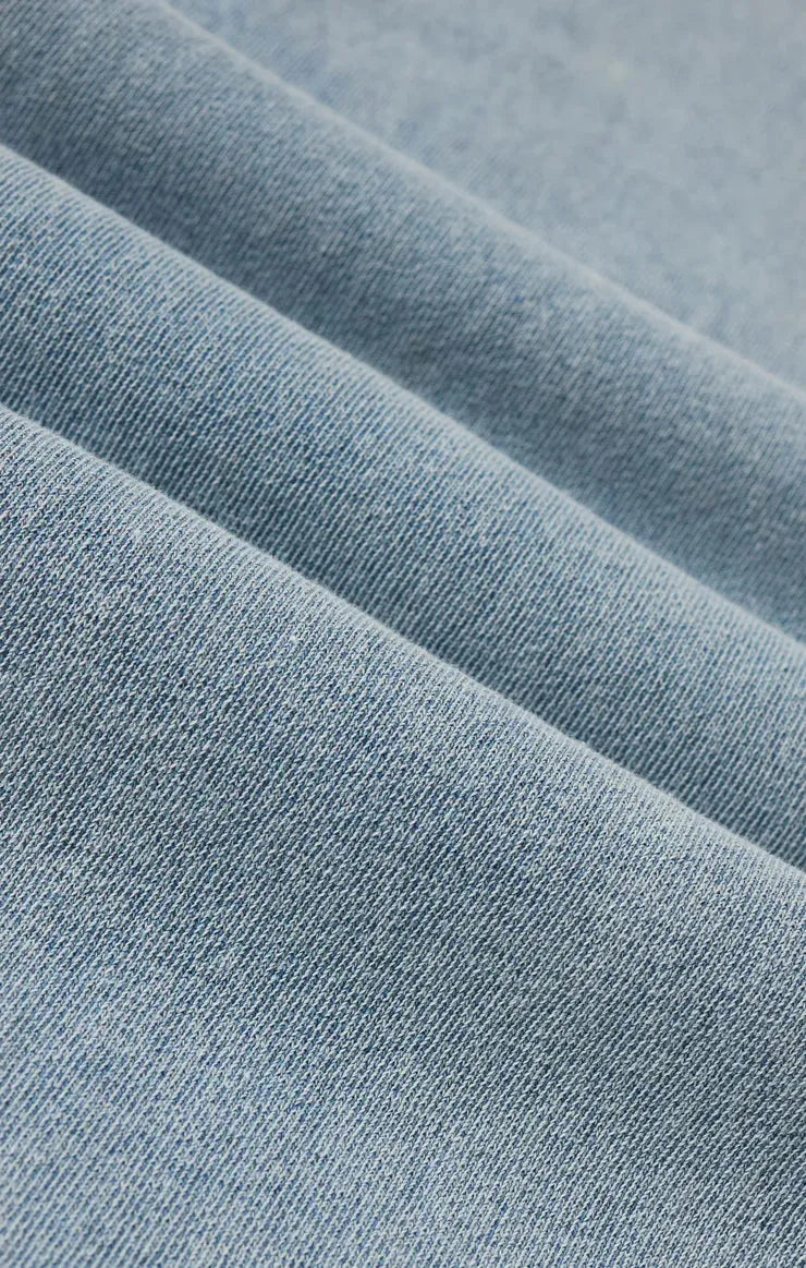 Soft light blue heritage knit denim jacket fabric with subtle textured weave showcasing premium knit denim material