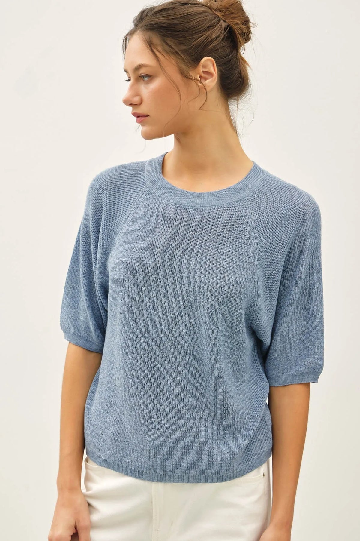 A soft light blue lightweight ribbed knit raglan short sleeve top with a round neckline and textured fabric