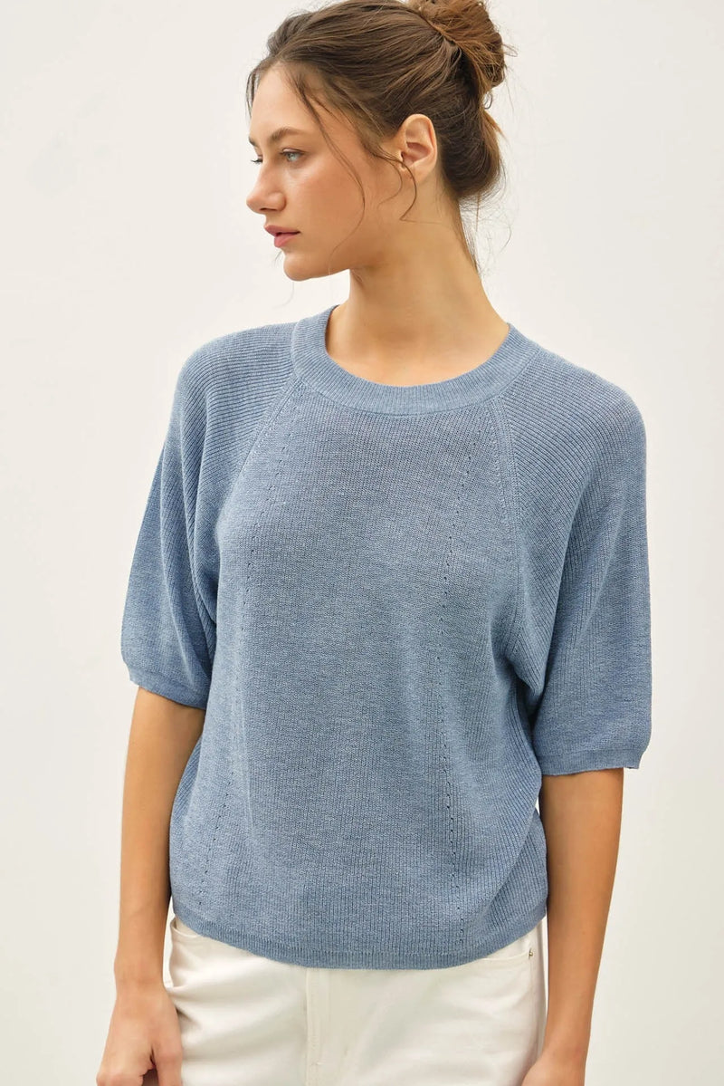 A soft light blue lightweight ribbed knit raglan short sleeve top with a round neckline and textured fabric