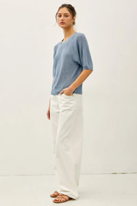 A soft light blue lightweight ribbed knit top with subtle texture and three-quarter sleeves in ribbed knit raglan style